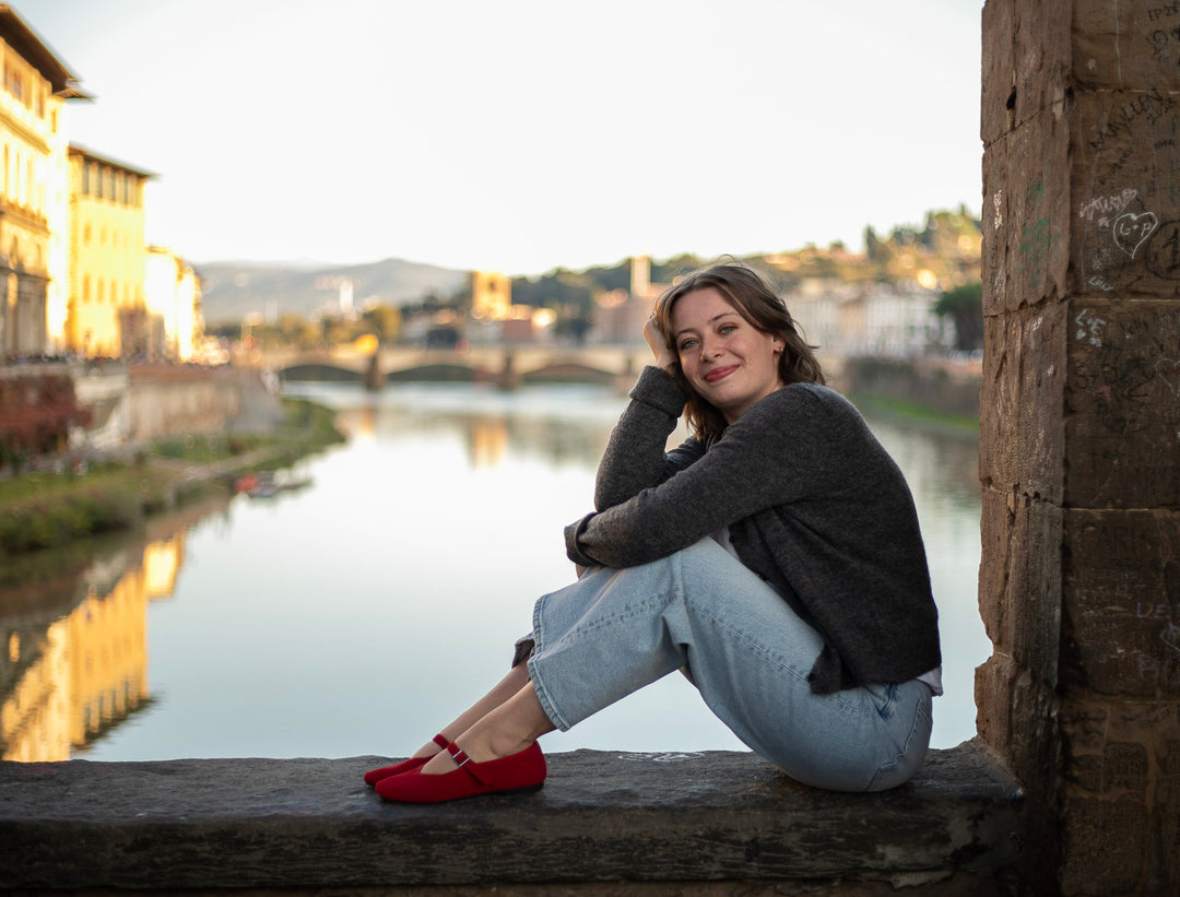 Catalin, gluten-free travel consultant, sitting on a wall by the river in Italy