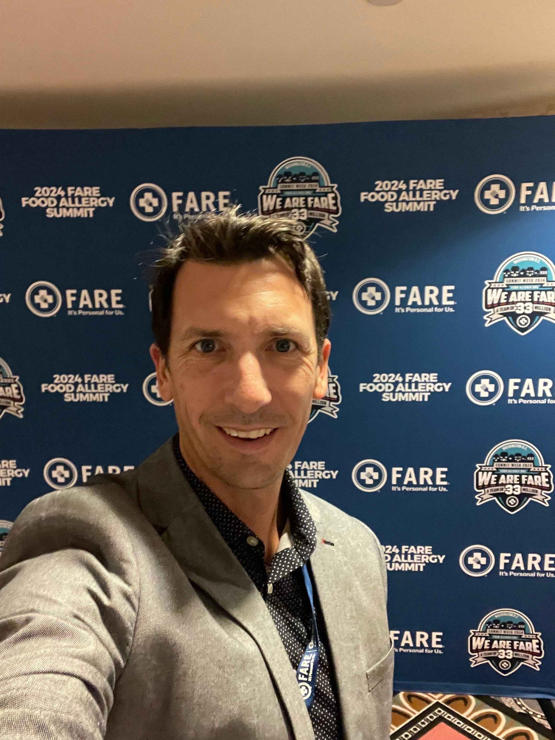 Kyle Dine in front of the blue FARE Food Allergy Summit banner